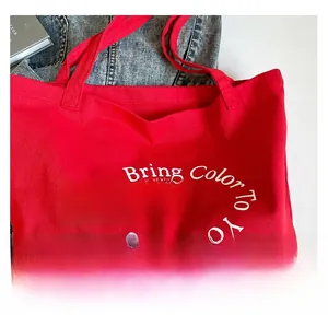 Flat lay of a red canvas tote bag with 'Bring Color To Your Life' white lettering
