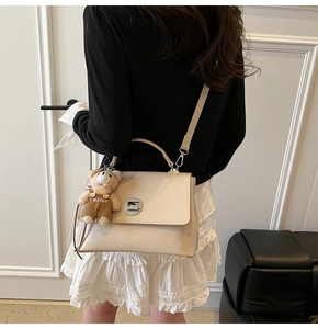 Cream white shoulder bag with silver turn-lock, top handle and plush bear charm detail