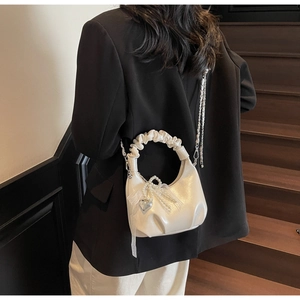 Detail of pleated handle cream white handbag with silver heart pendant and pearl tassel