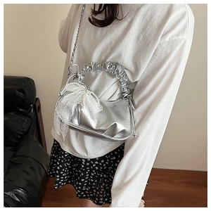 Detail of silver metallic pleated cloud bag with white lace bow and pearl charm