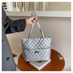 Detail of silver quilted tote bag with metallic finish and brand metal tag