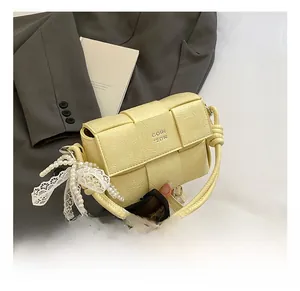 Détail du sac tissé crème avec pendentif raffiné en perles et nœud en dentelle