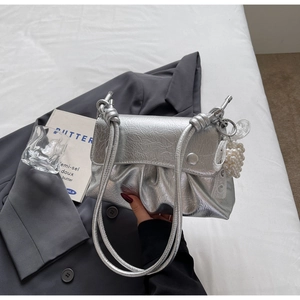 Détail du sac à main plissé argenté avec breloque cœur en perle et fini métallisé