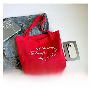 Detail of red large capacity canvas tote bag with artistic letter print and sturdy handles