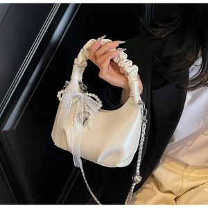 Detail of white pleated moon bag with lace bow, pearls, and silver heart pendant charm