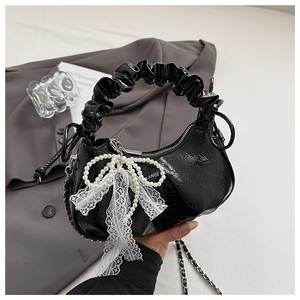 Detail of black patent leather cloud bag with pearl bow and lace ribbon accent