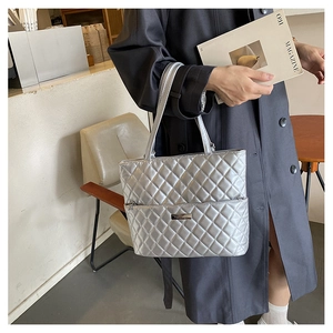 Detail of silver quilted tote bag with metallic finish and metal logo on a model