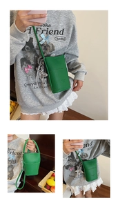 Detail of green pebble leather mini crossbody phone bag with metal bow tassel charm