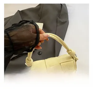 Détail du sac à main tressé jaune pâle en cuir avec pendentif décoratif en perle et dentelle