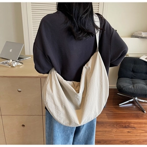 Rear view of a model wearing a large beige woven tote bag in a modern workspace setting