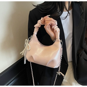 Detailed macro view of the pearlescent pink gathered handbag with elegant pearl accessories