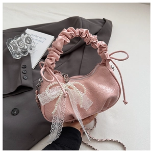Detail of pink ruched cloud bag featuring lace bow, pearl accents and silver chain strap