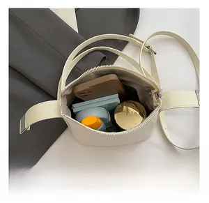 Detail showing the internal storage capacity of the beige oval crossbody bag with essentials