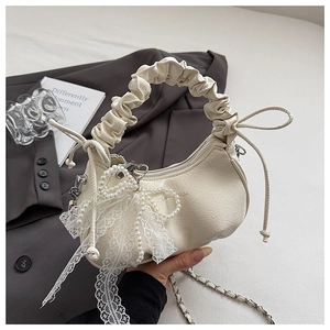 Close-up of cream pleated hobo bag featuring lace bow and pearl pendant detail