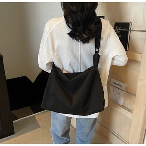 Minimalist black large capacity crossbody bag shown on a model in a casual setting
