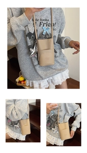 Detail of beige lychee leather phone bag with card slot and silver star charm