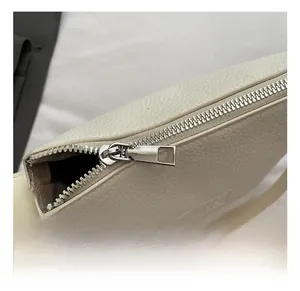 Detailed macro view of the silver metal zipper and white litchi grain leather texture
