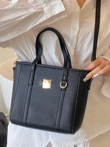 Minimalist black pebble leather tote bag with gold hardware and a detachable shoulder strap