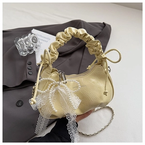 Detailed close-up of yellow pleated cloud bag with pearl bow and lace ribbon details
