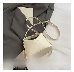 Close-up of cream textured leather handbag with silver hardware and embossed logo
