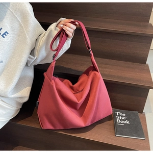 Detail of burgundy canvas crossbody bag texture and strap on a wooden staircase