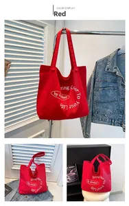 Detail view of red canvas tote bag with white circular slogan and durable shoulder straps