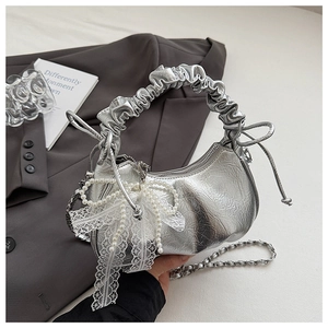 Detail of silver metallic cloud bag with pearl bow, lace trim, and pleated handle design
