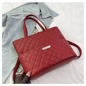 Close-up of red quilted tote bag with diamond pattern on denim jacket background