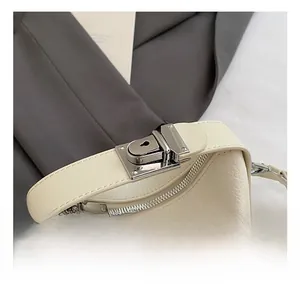 Detail of cream lychee leather handbag showing silver lock and reinforced handle joint