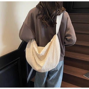 Detail of cream woven crescent tote bag with textured seersucker fabric and soft structure