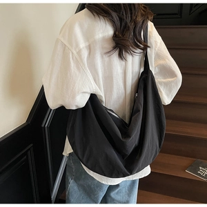 Minimalist black crescent crossbody tote bag in nylon with wide shoulder strap on model