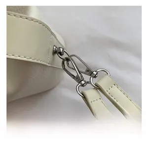 Close-up of premium silver hardware hook and litchi texture on a white handbag