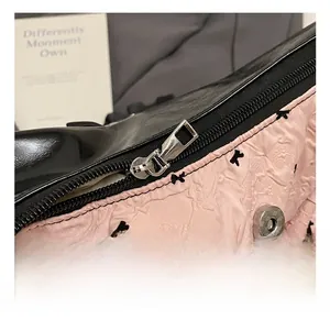 Detail of pink pleated fabric with bow print and shiny black panel on a tote bag