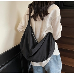 Model view of large black crescent tote bag showing size and drape on the shoulder