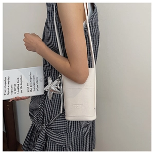 Creamy white litchi pattern mini bag with star pendant on model's shoulder