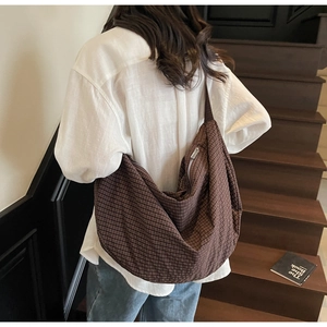 Detailed close-up showing the brown checkered texture and silver zipper of this hobo bag