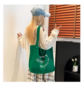 Detail of green canvas tote bag featuring white printed text and a minimalist artistic design