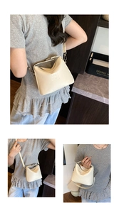 Detail of off-white lychee leather crossbody bag with metal handle and embossed logo