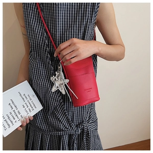 Detail of red pebbled leather mini bucket bag with silver star charm and embossed text