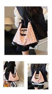 Pink tote bag detail with 3D black bows, heart pendant, and model's shoulder carrying style