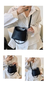 Detail of black bucket bag featuring litchi texture leather and adjustable strap