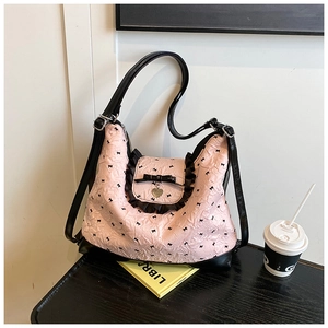Close-up of pink tote bag featuring black bow patterns and metal heart pendant