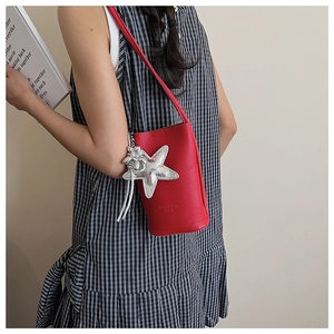 Detail of red lychee pattern bucket bag with a shiny silver starfish pendant and logo