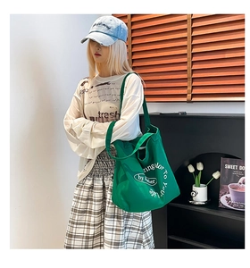 Detailed view of large green canvas tote bag styled with casual outfit for daily commute