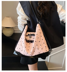 Detailed macro view of pink tote bag with floral embossing and black bow accents