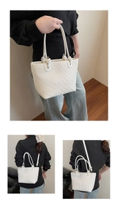 Macro detail of white woven texture tote bag showing handles and adjustable strap