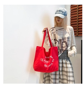Detail of red canvas tote bag with white typography showing thick material and large capacity