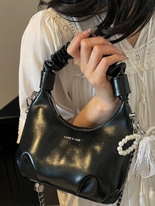Elegant black crescent hobo bag with pleated handle, pearl chain, and shimmering finish