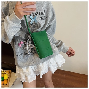 Detail of green litchi texture leather phone bag with silver star charm accessory