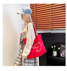 Detail of red canvas tote bag with artistic letter print in a casual lifestyle setting